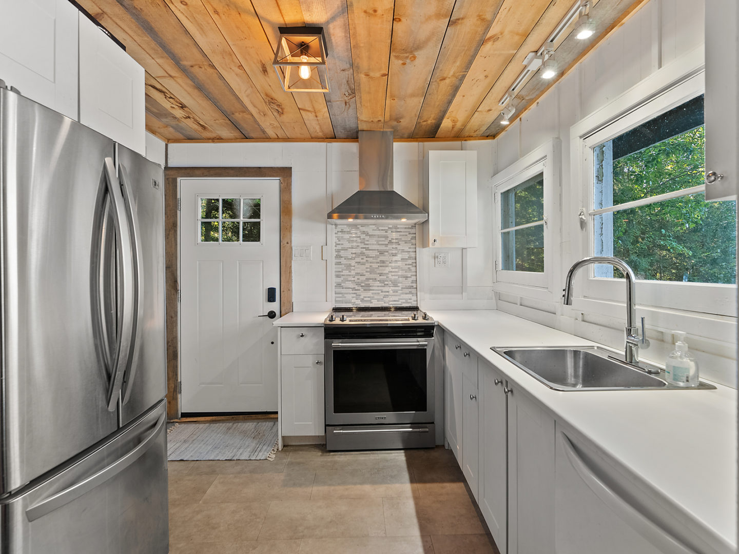 A small kitchen with modern stainless steel appliances and white cupboards.