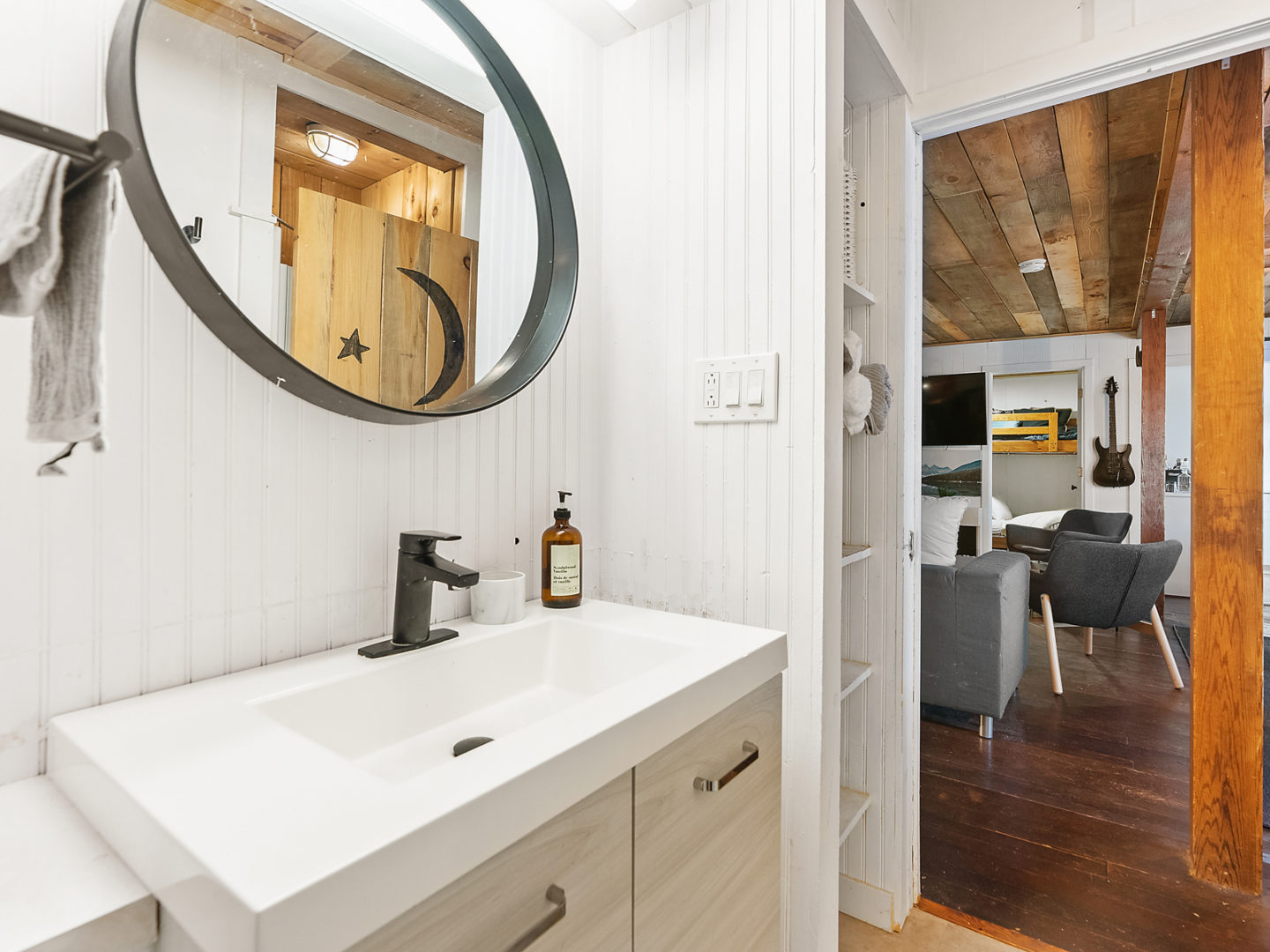 A bathroom sink with a large circular mirror over top.