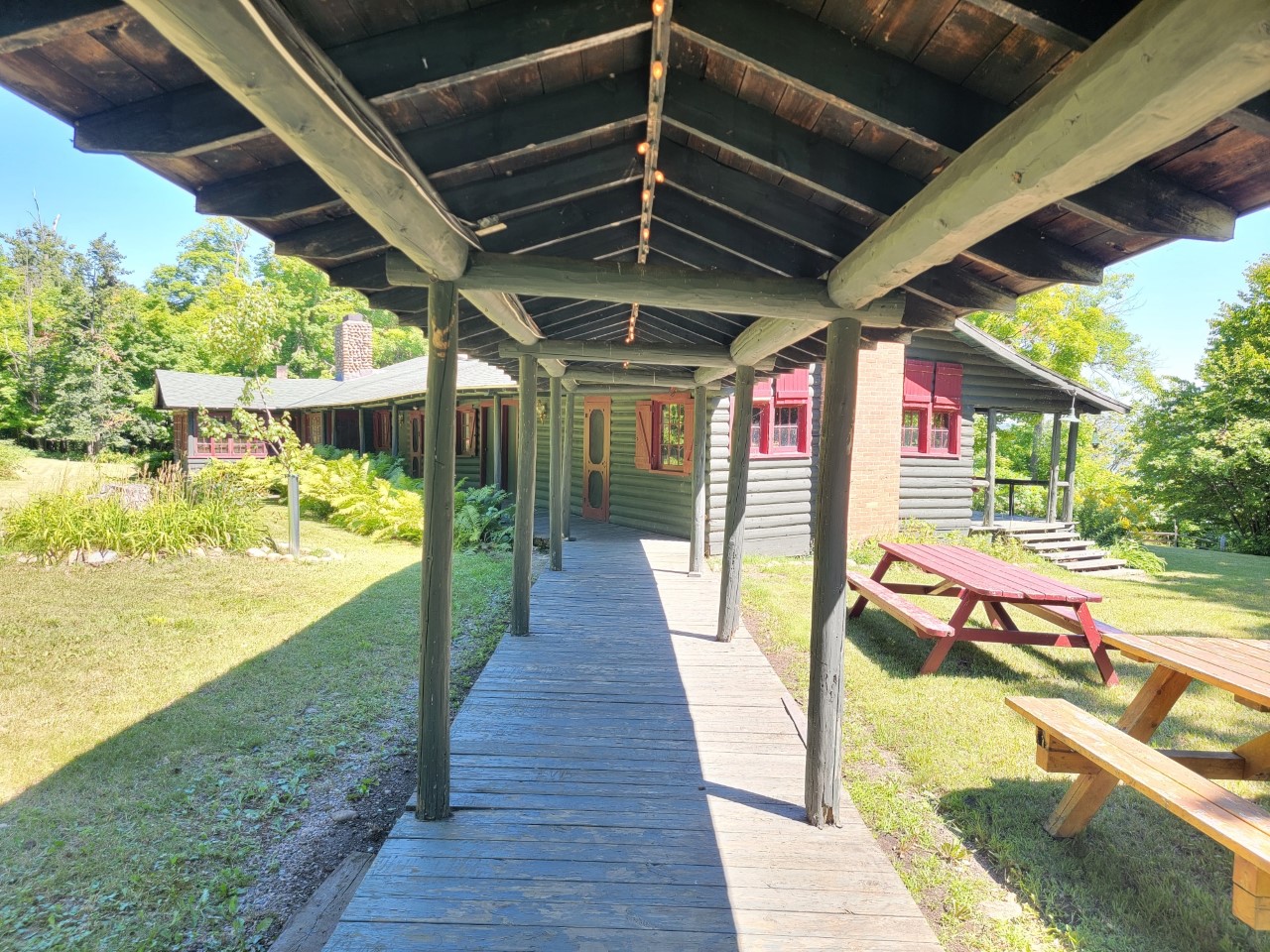 A long covered walkway connects two buildings of a spacious one-story cottage.