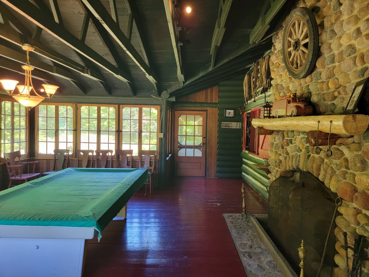 A large room with a fireplace, a pool table, and lots of windows.