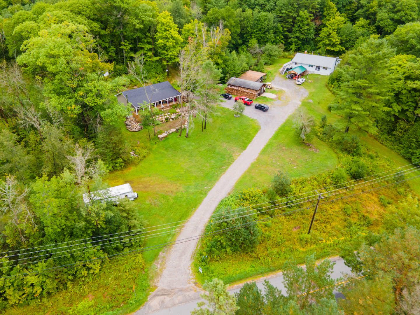 A long road going through a grassy area, leading to a small cottage.