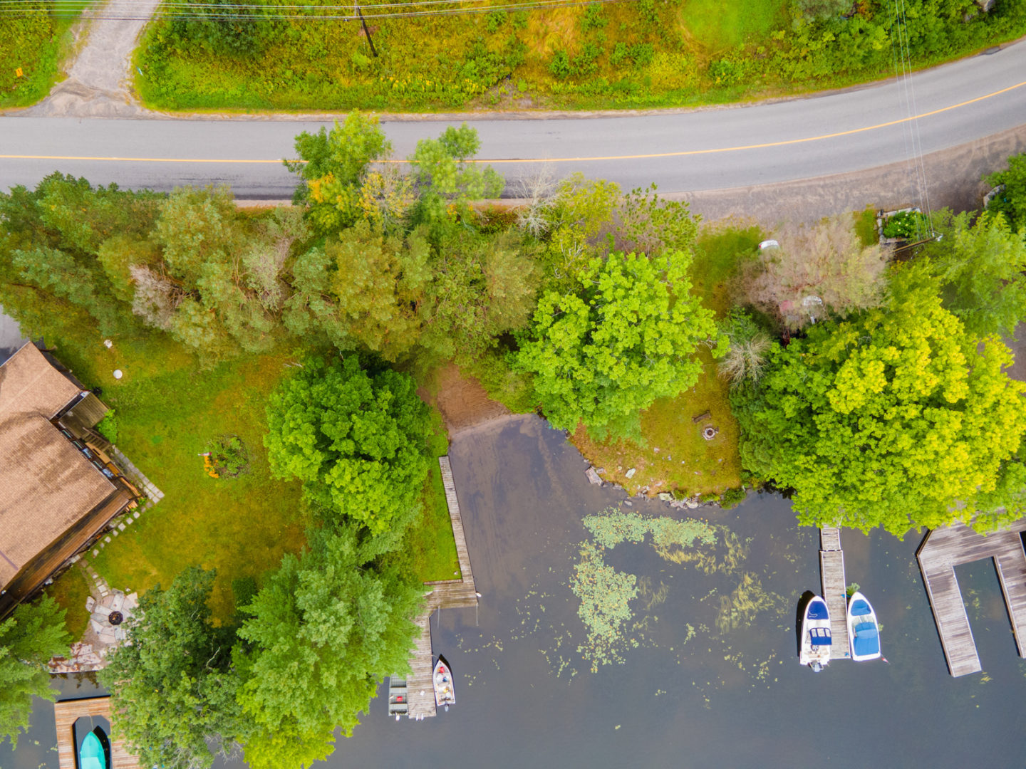 An overhead view of a small lakefront area, with a sandy shore and a log dock.