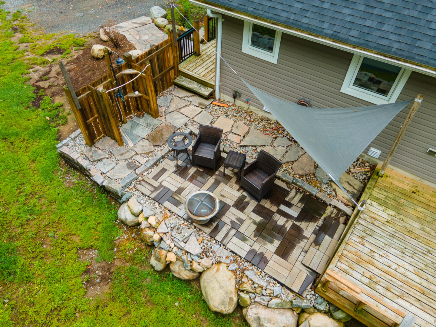 Overhead view of a small back patio with chairs, a fire pit, and an outdoor shower off to the side.