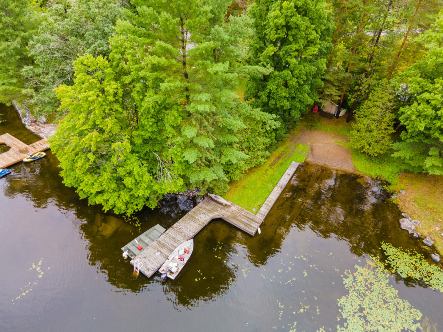 An overhead view of a small, quiet waterfront area with a sandy shore and a long dock.