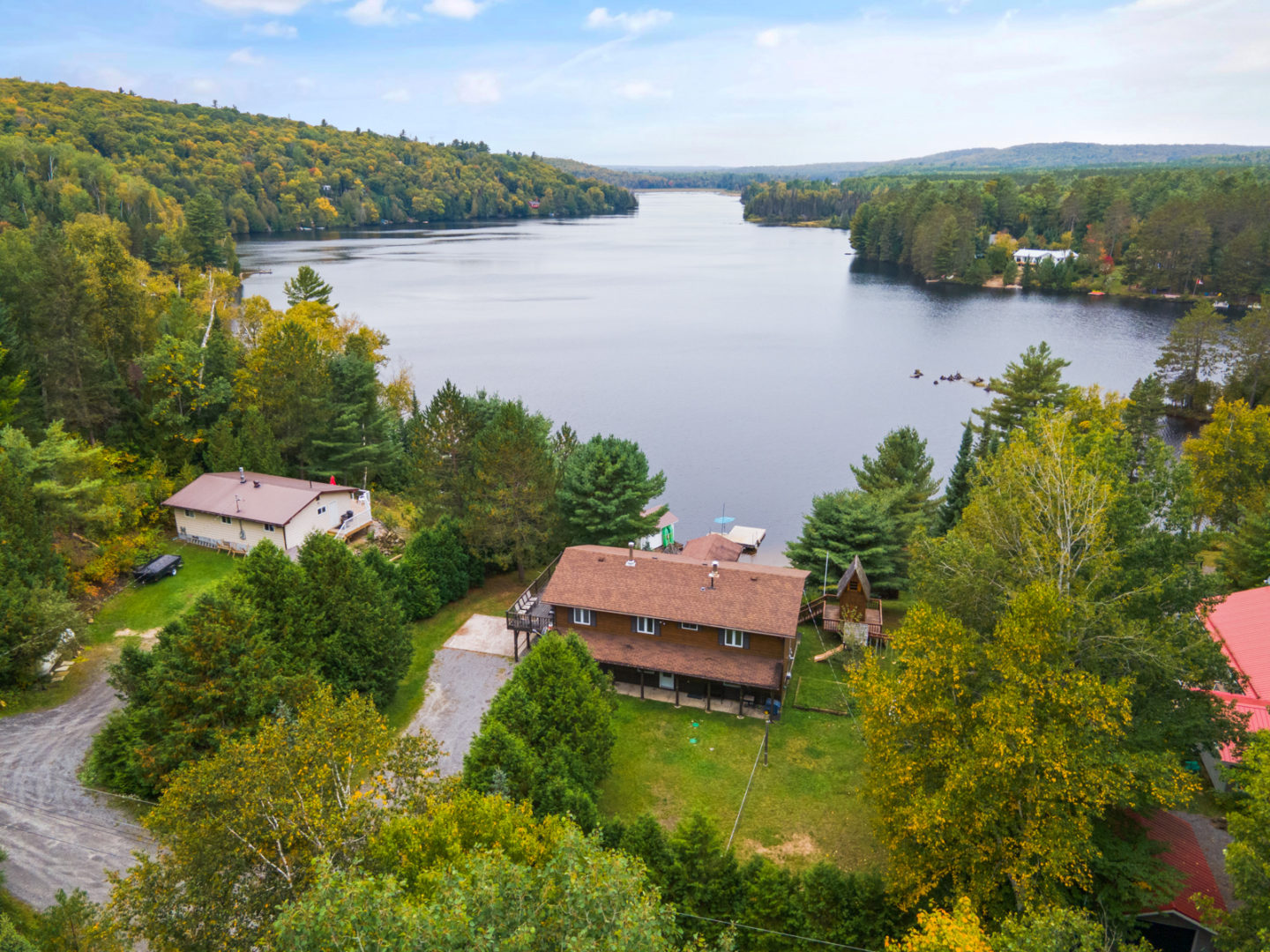 A house with a large backyard, on top of a hill in front of a lake.