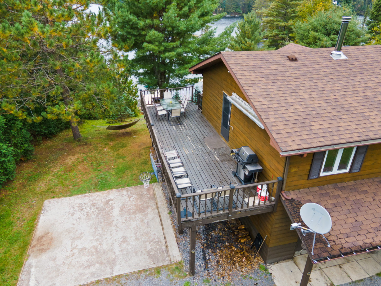 A small basketball court below a second-level deck, attached to a two-storey house.