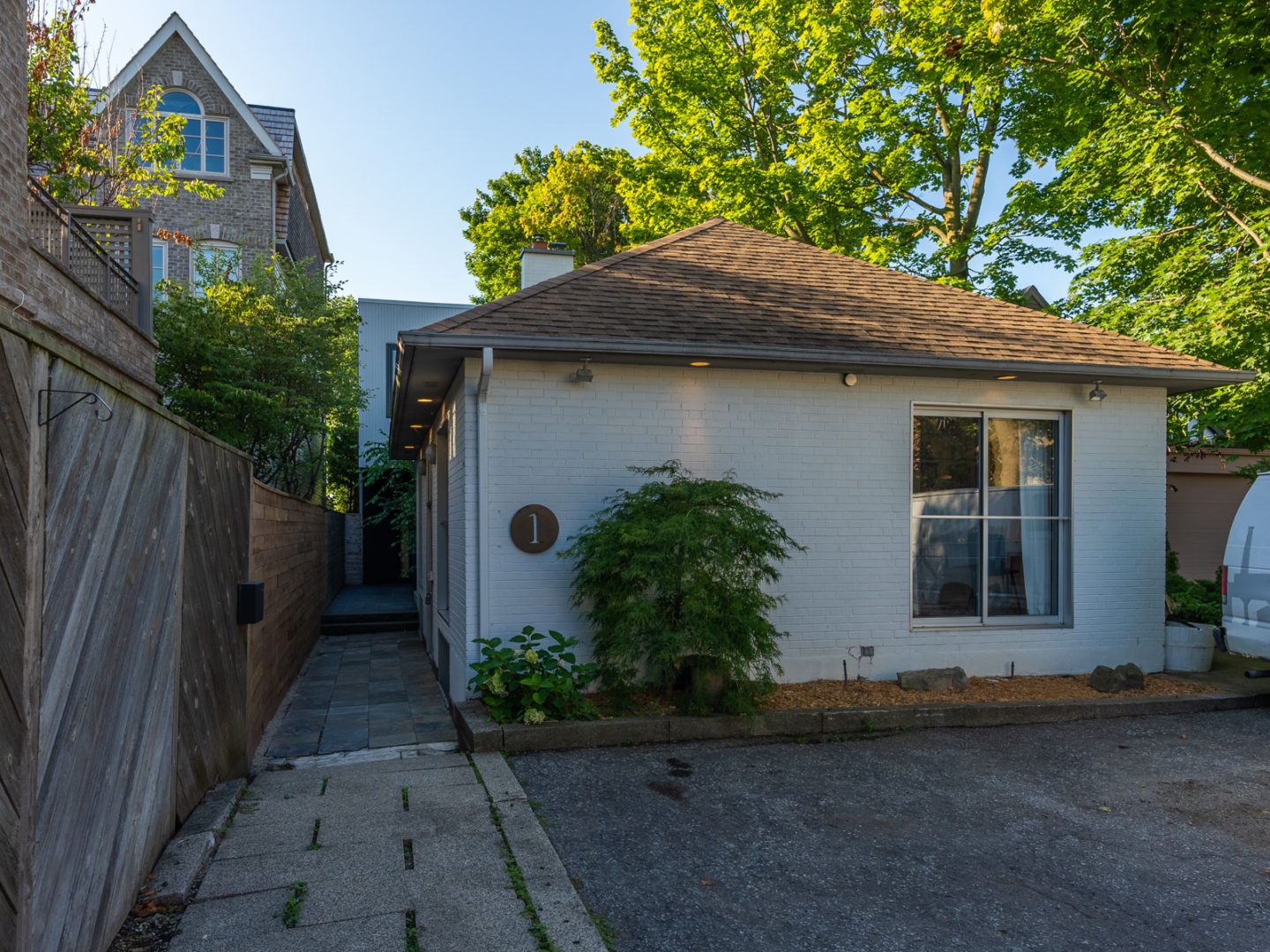 A modest-looking bungalow with a white-painted exterior and a brown roof.