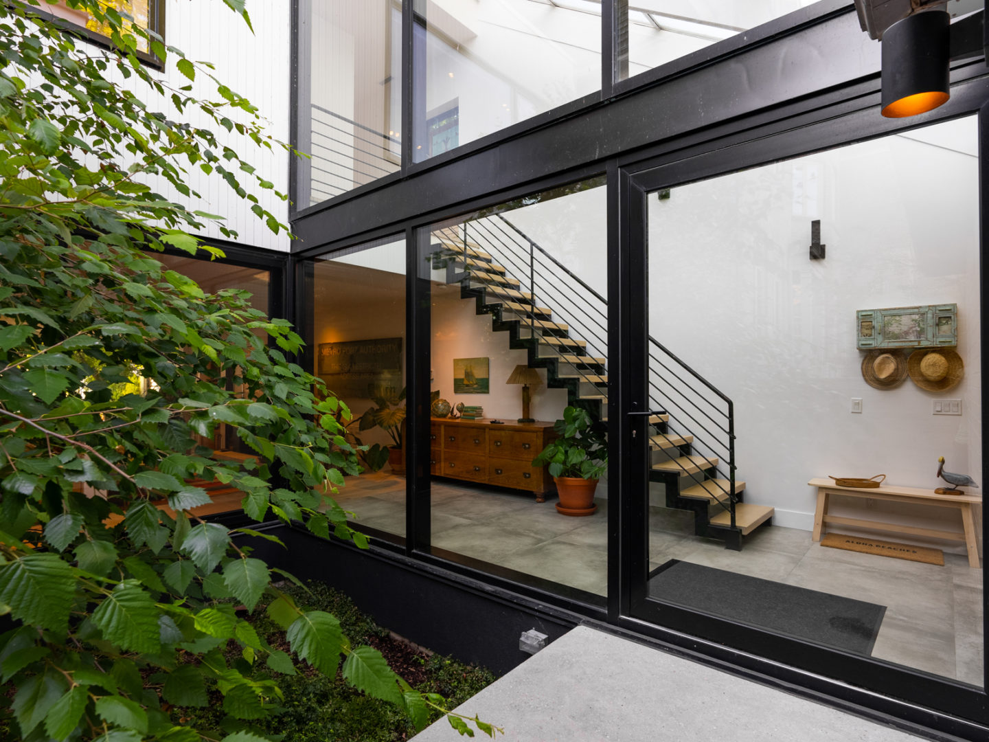 A staircase in a hallway, seen from a small outdoor patio through a wall of windows.