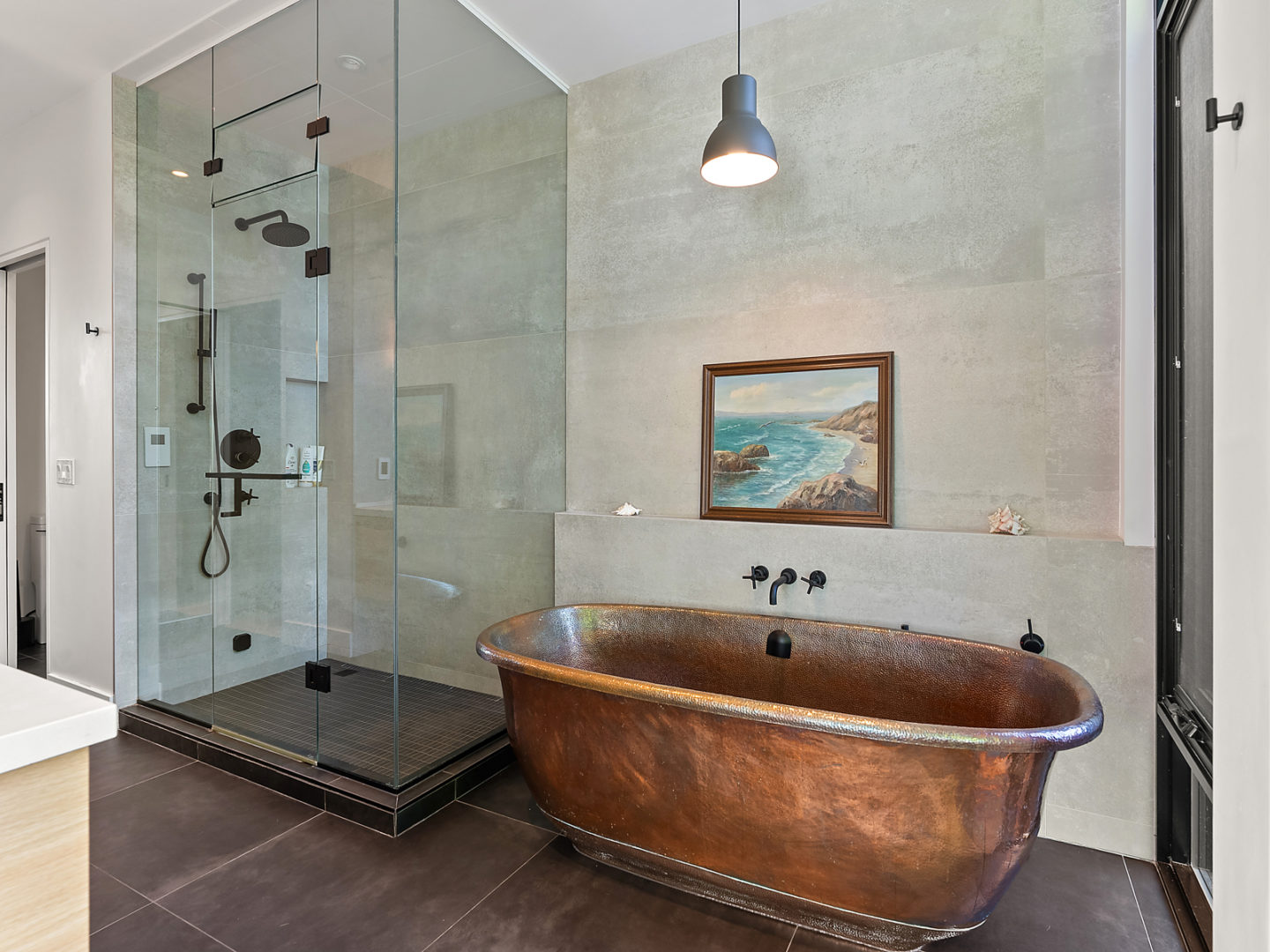 A free-standing, copper-coloured bathtub with a large walk-in shower to the right of it.
