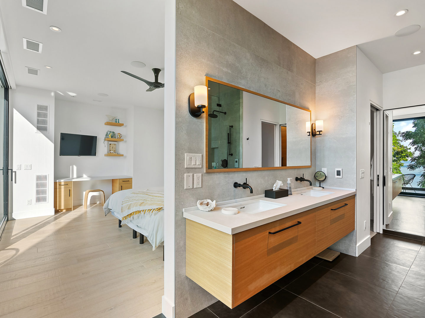 A passage between a bedroom and a bathroom, with a large sink seen on one side of the wall and a big bedroom past the doorframe.