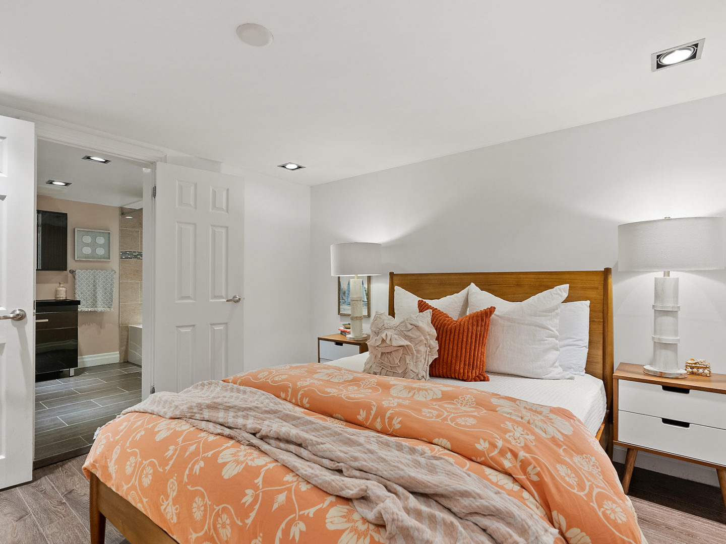 A small bedroom with a large bed that has a peachy pink duvet.