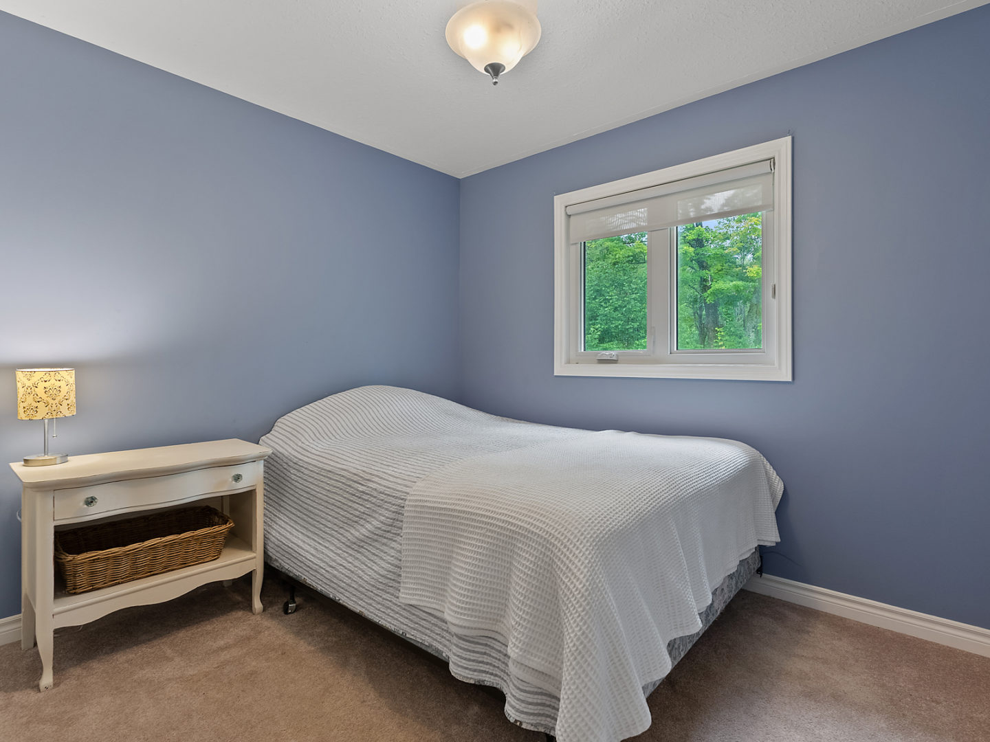 A small bedroom with a single bed and a large window.