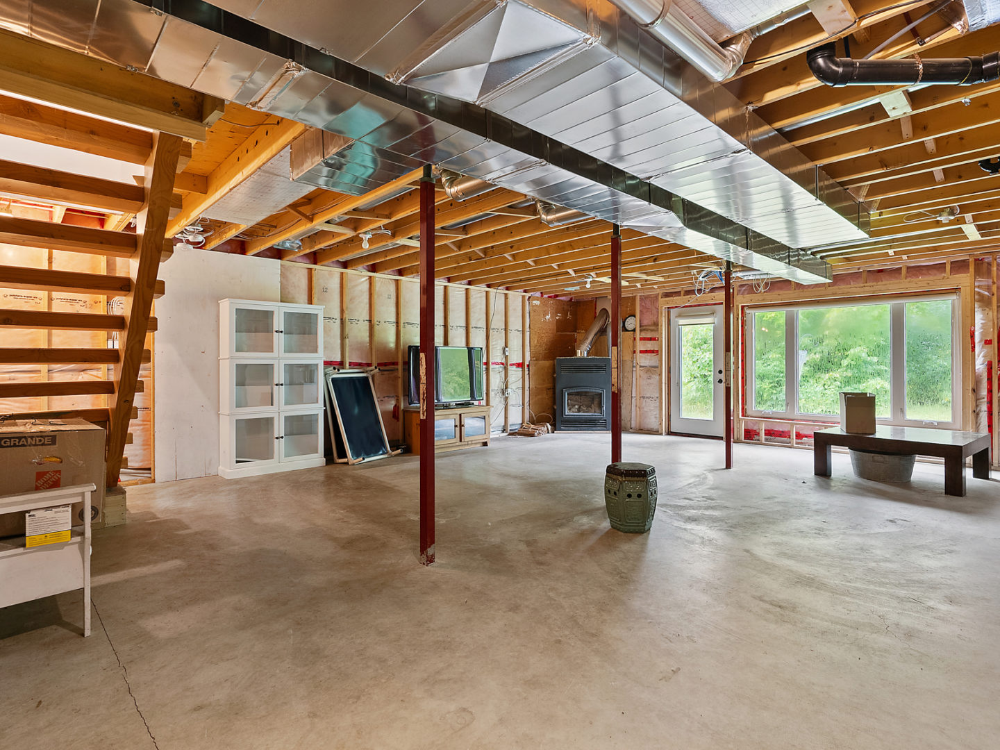 A half-finished basement area with exposed ceiling beams and a fireplace in the corner.