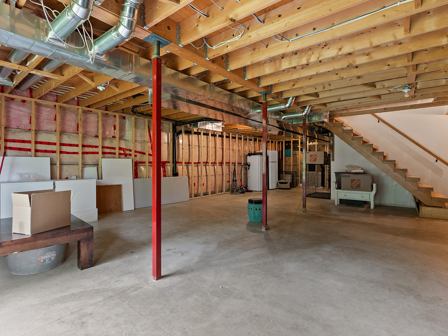A large half-finished basement area with exposed beams in the walls and ceiling.