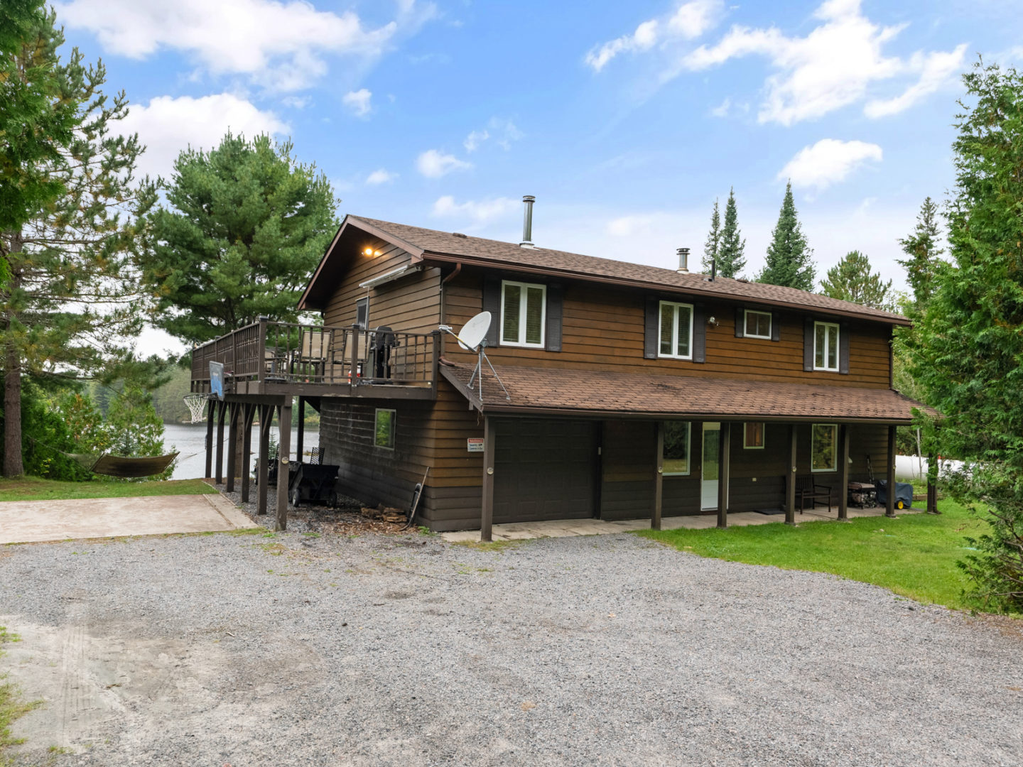 A two-storey home with a large driveway and a big deck on the second level.