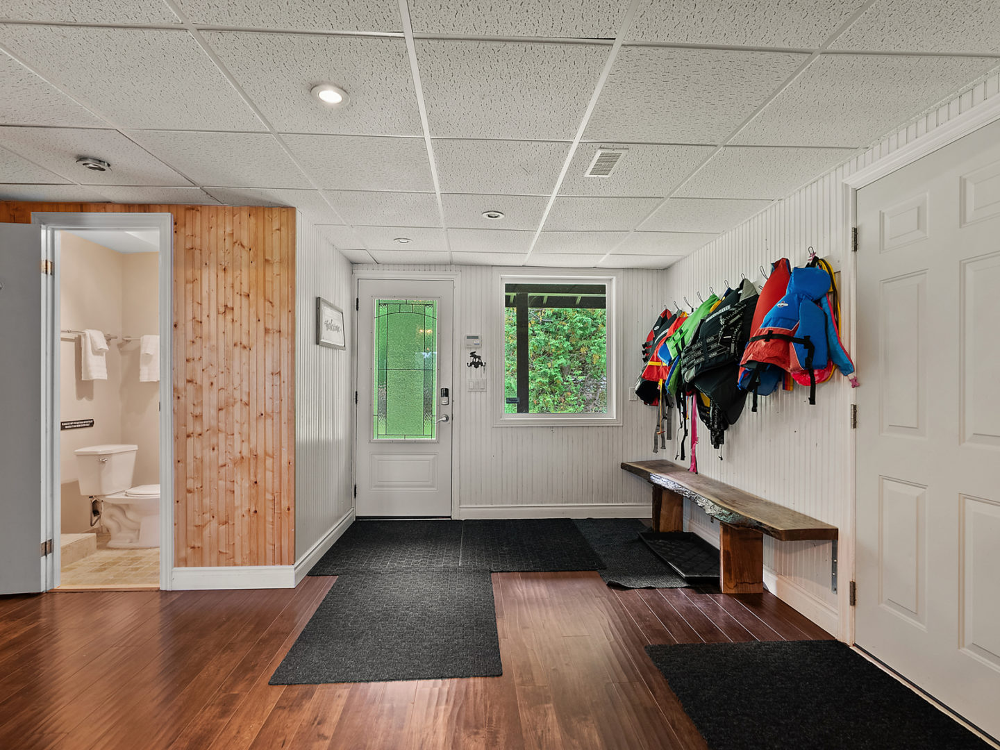 A large foyer area with wood floors, a door leading outside, a coat area, and a bathroom off the entrance.