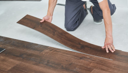 A man installing pieces of vinyl flooring on a sub-floor