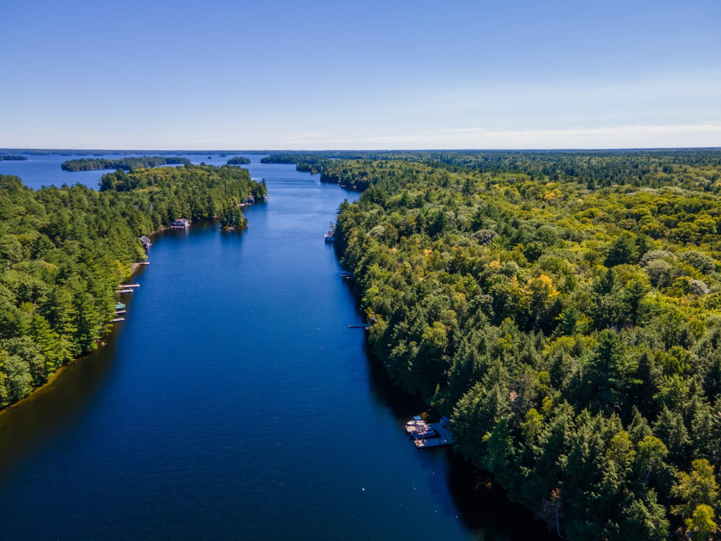 Overhead view of a narrow stretch of blue lake, flanked on either side by dense green trees.