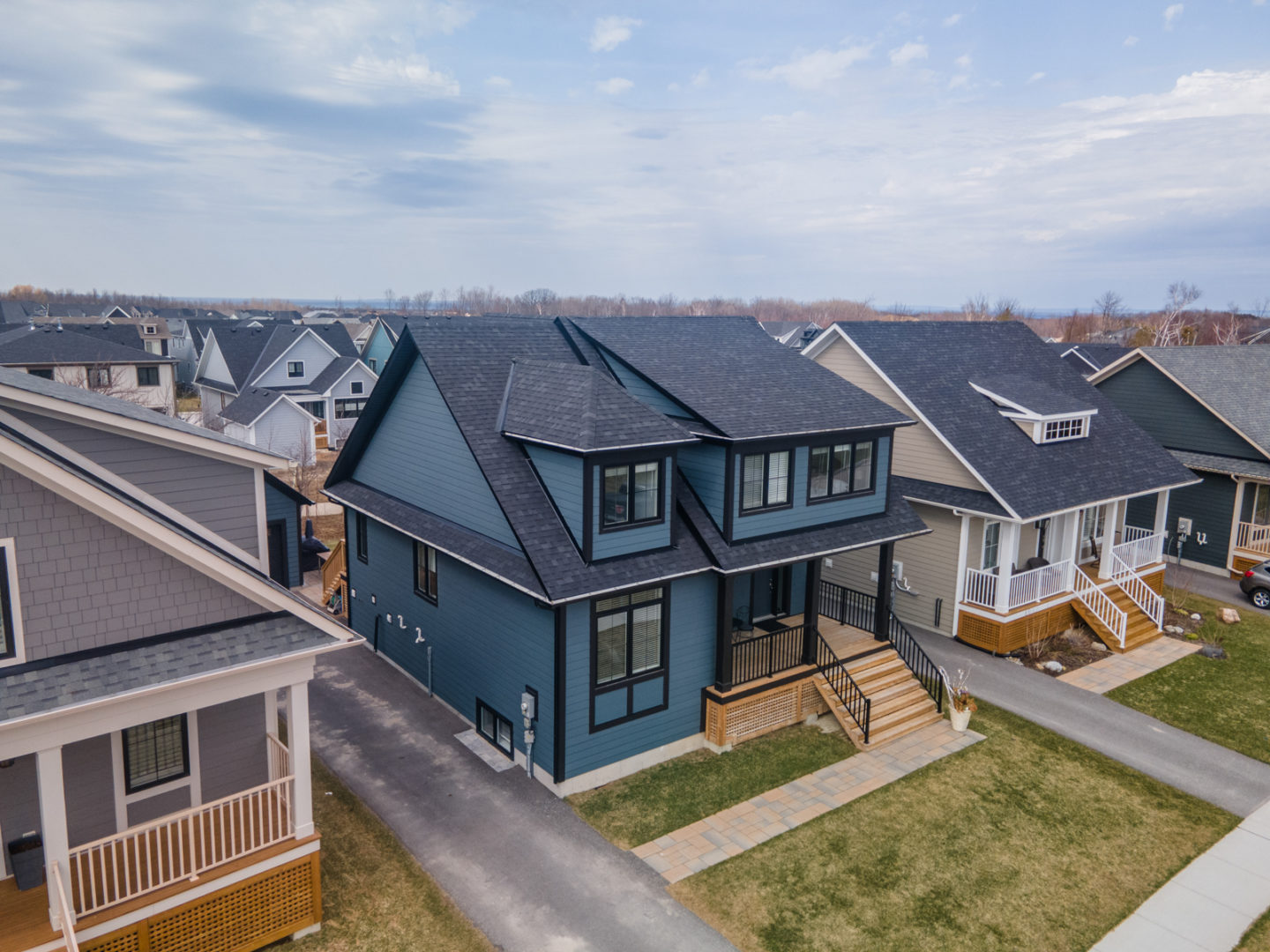 Overhead view of a two-story home on a suburban street, with dark blue exterior siding. The roof and window trim are black.