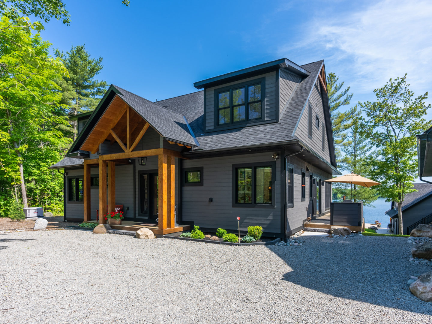 Exterior of a large, modern, two-story cottage with a dark grey colour palette and warm wooden accents framing the front entrance.