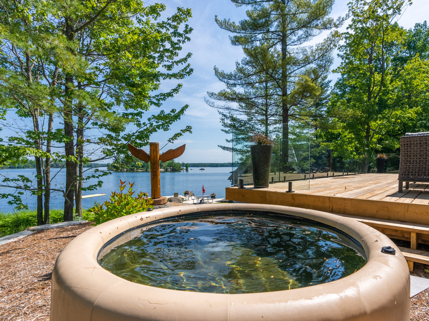 A small round hot tub with leather-like exterior, facing out towards a lake.