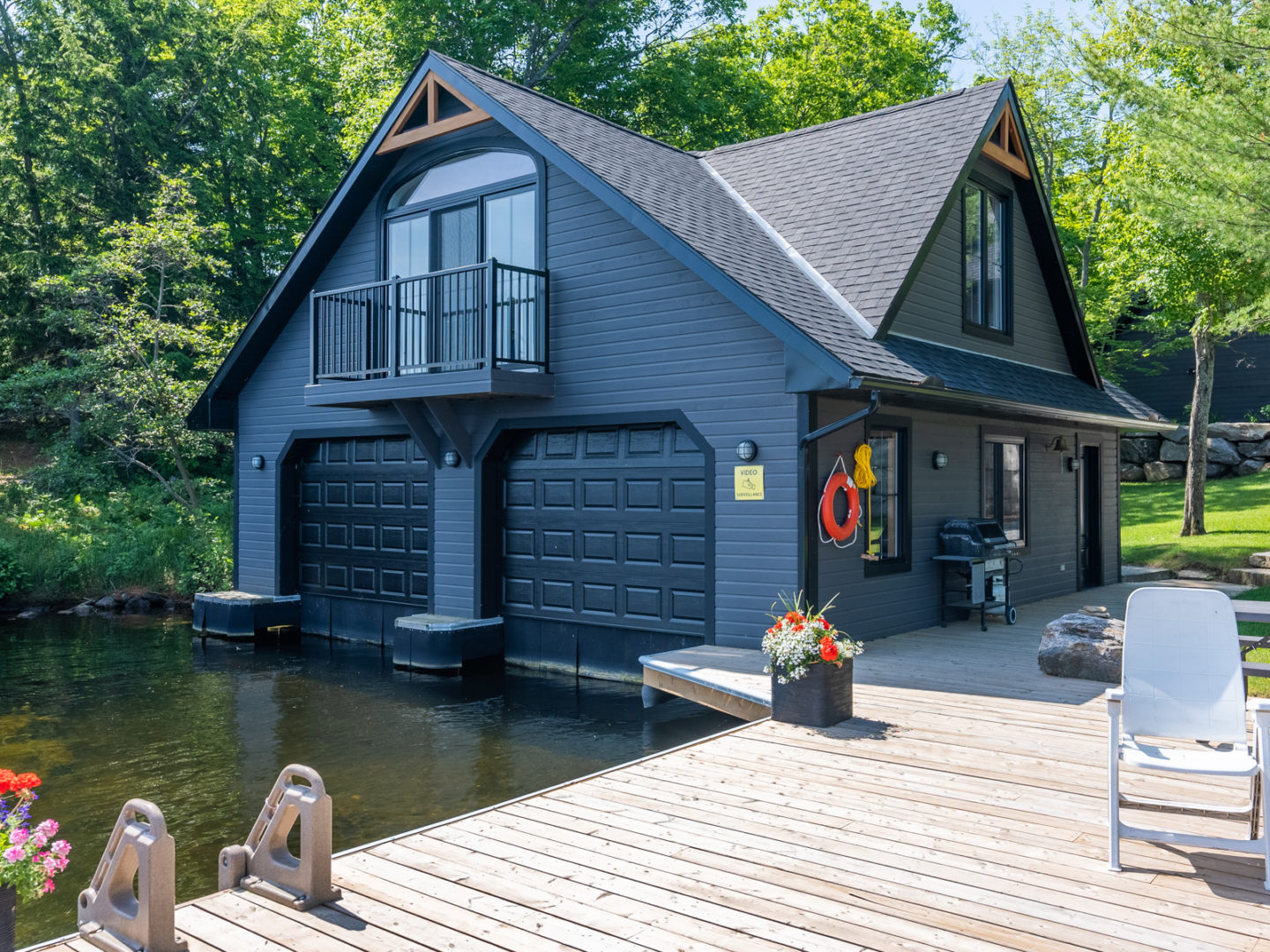 A large boathouse with two garage doors facing the water and a big wooden dock branching off the side.