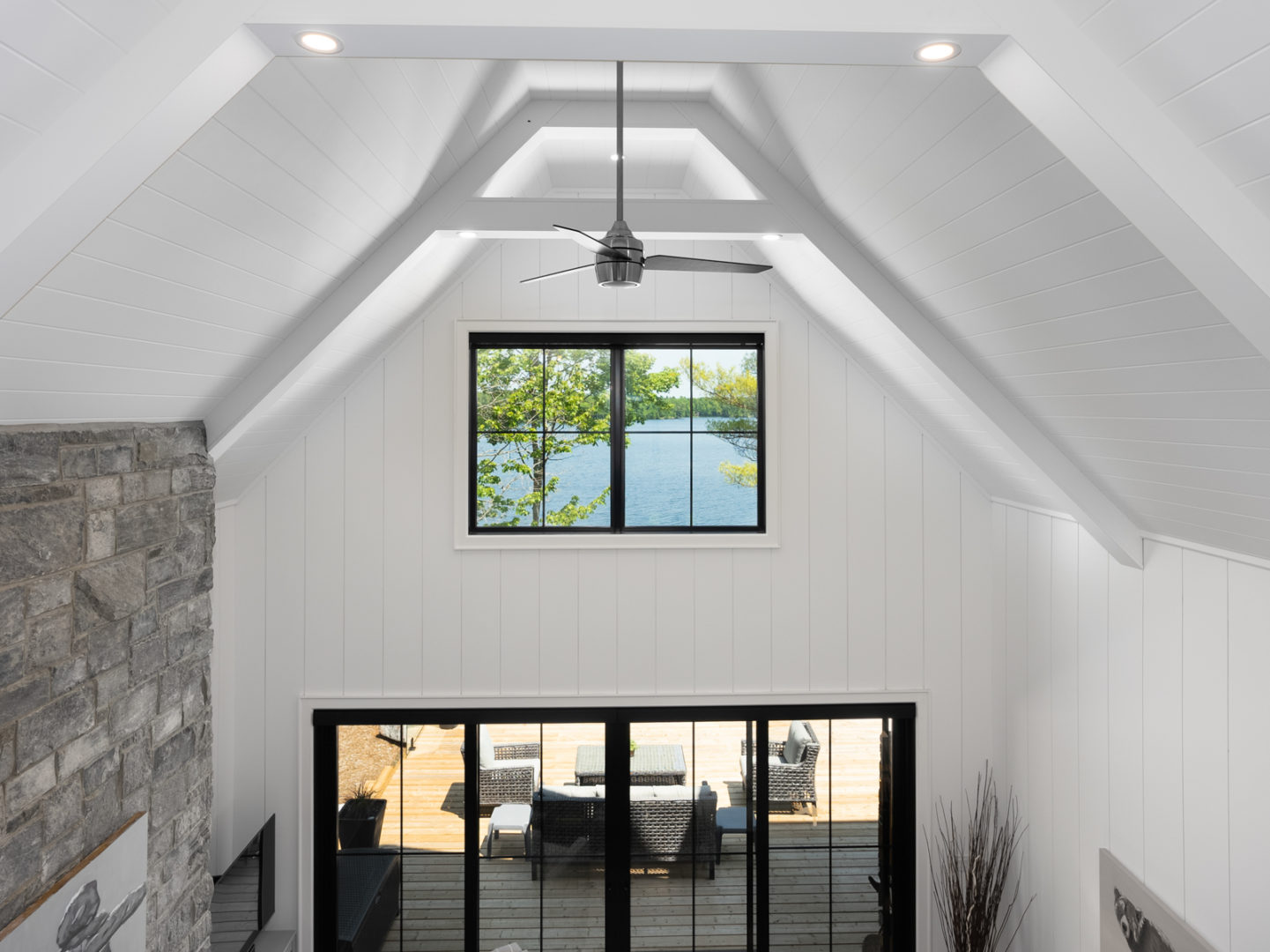 Looking out over a high-ceilinged living area with large windows, white walls, and a floor-to-ceiling fireplace.