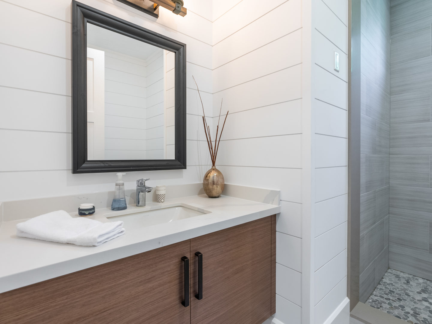 A modern bathroom with a small mirror above a sink and a shower.