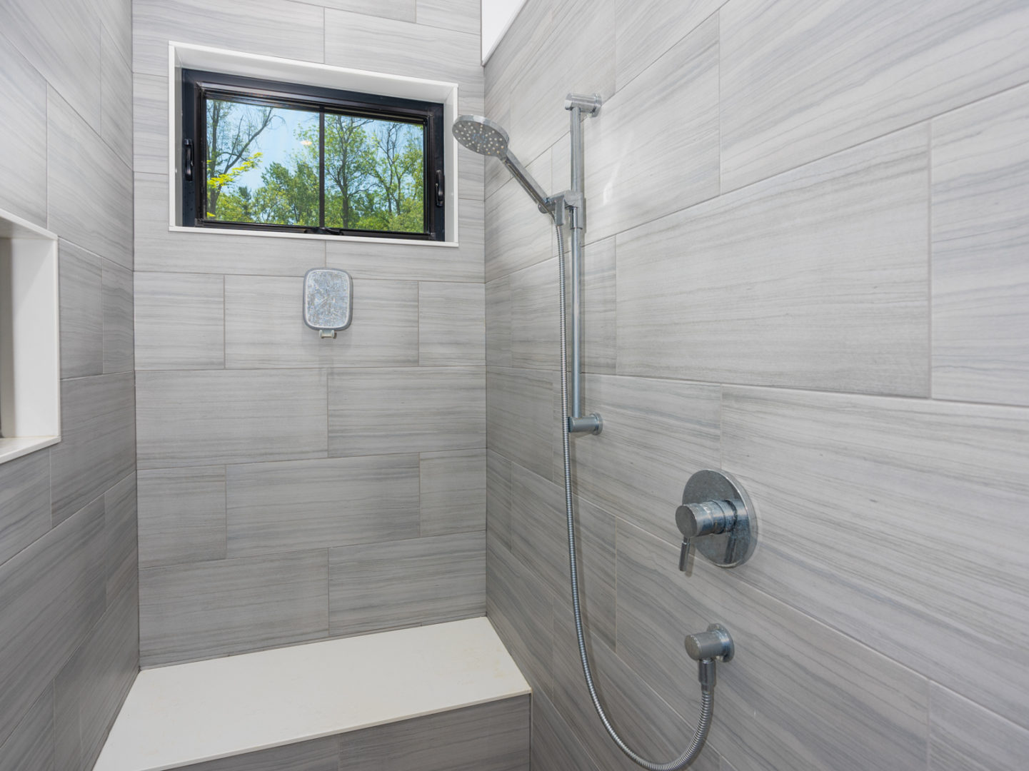 A large shower with grey walls and a rainfall shower head.