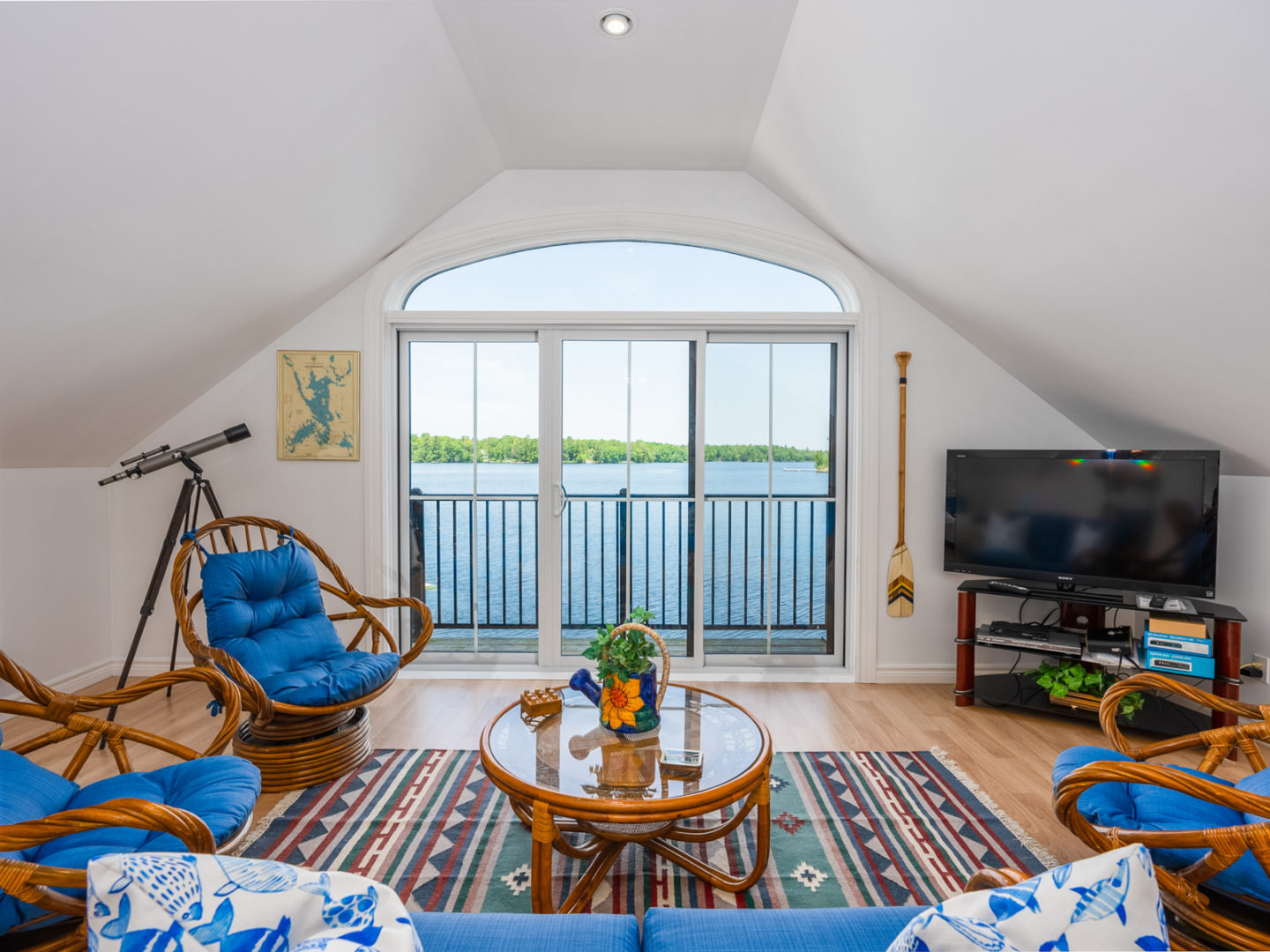 A bright living area with large glass doors that open out to a balcony overlooking a lake.