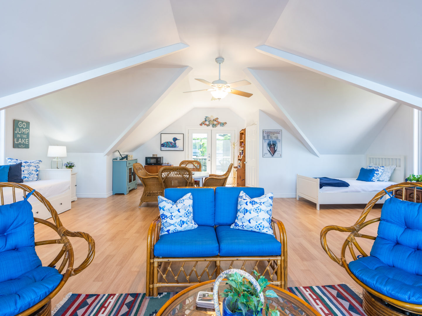 A bright living area with a table and chairs, couches, and beds against the wall.