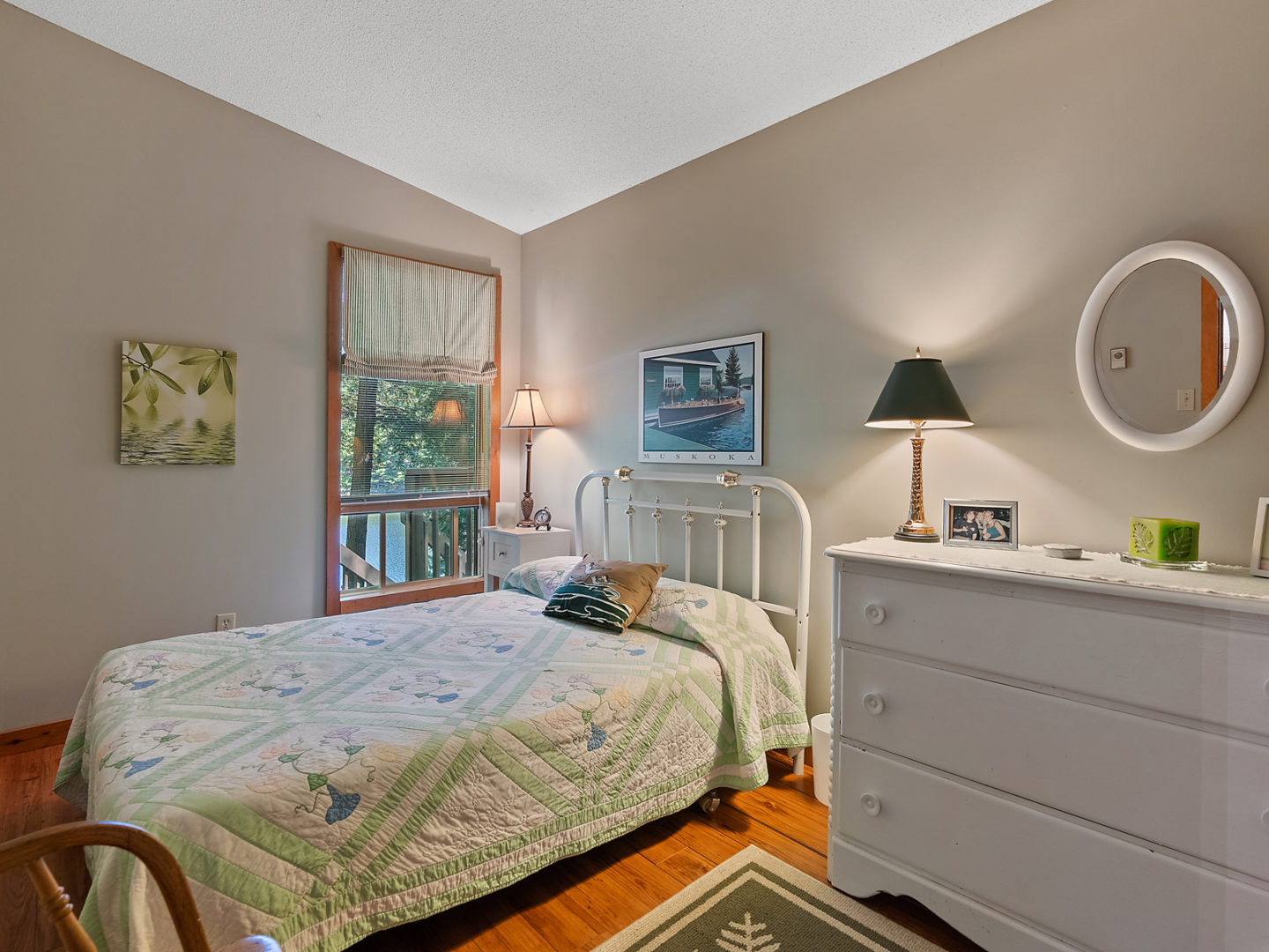 A small bedroom with a single bed, a white dresser, and a window beside the bed.