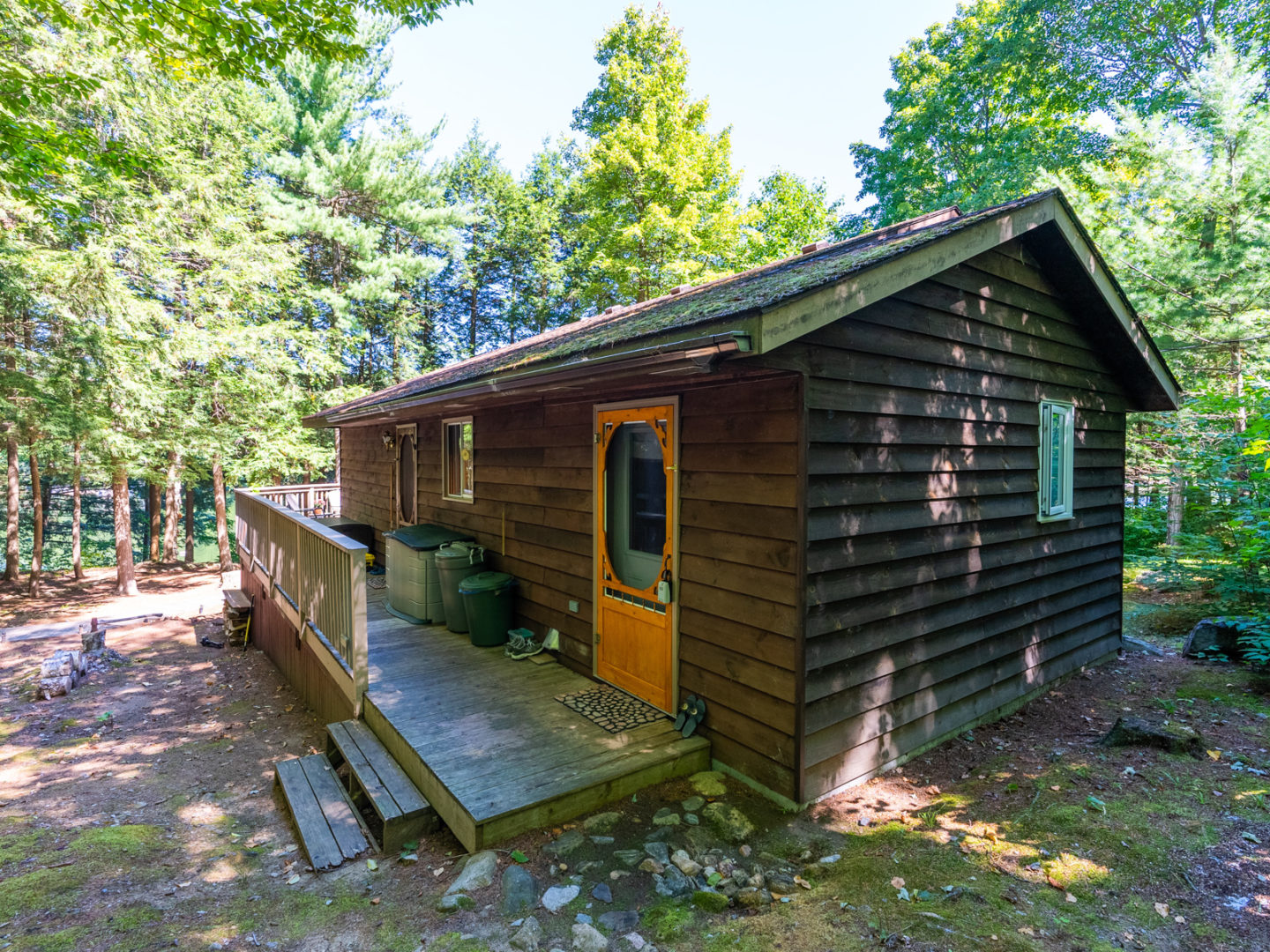 A wooden cottage with a long deck along the side, with two side-door entrances.