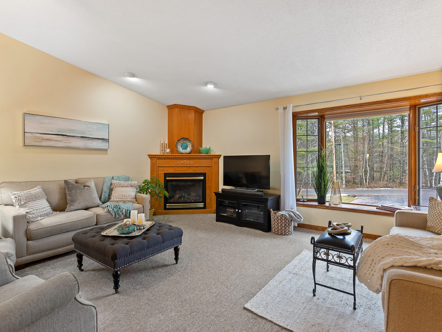A large living area with a big window, lots of seating, a fireplace, and a television.