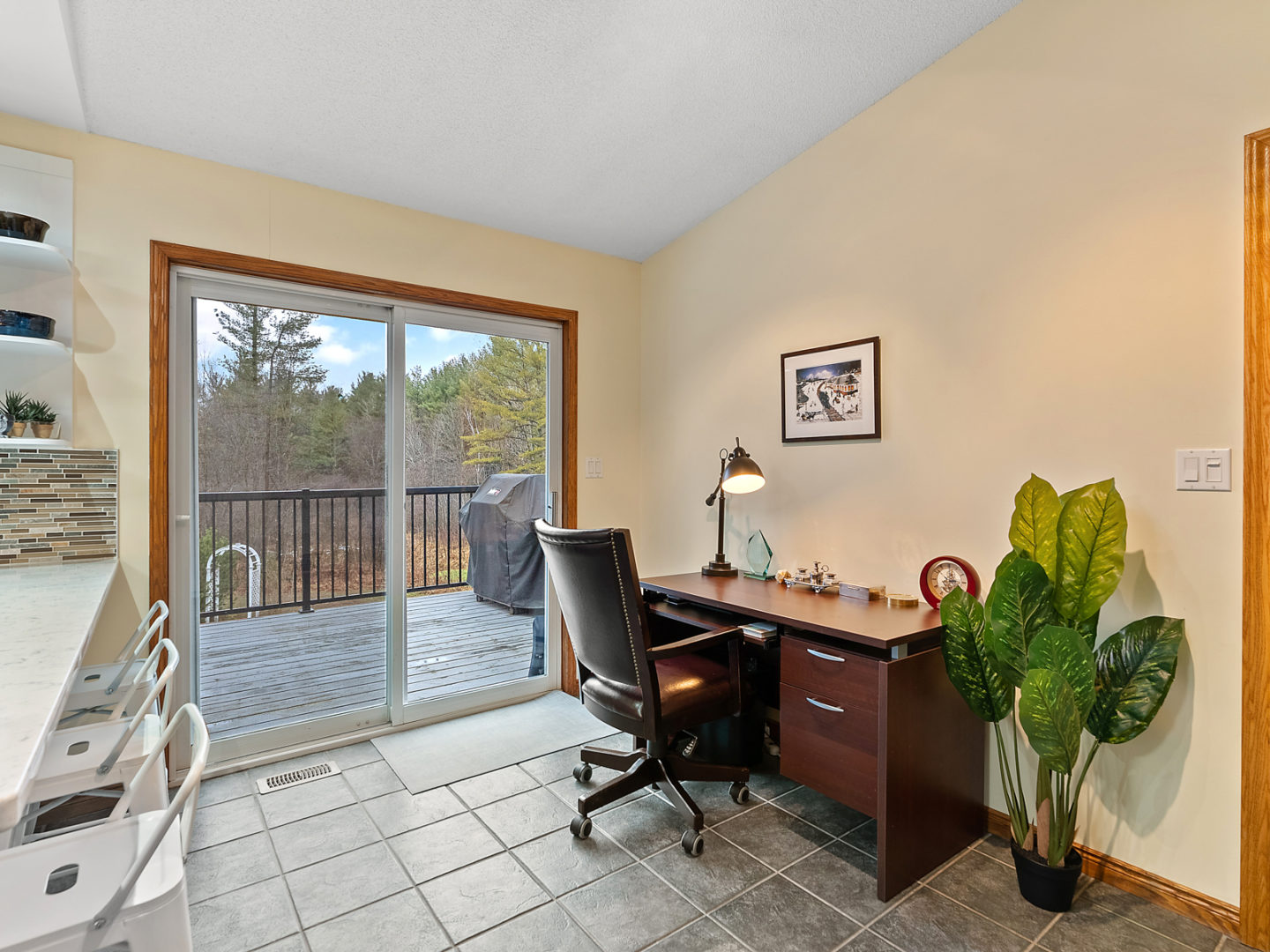 A desk at the back of a kitchen, located near sliding double doors that lead out to a big back deck.