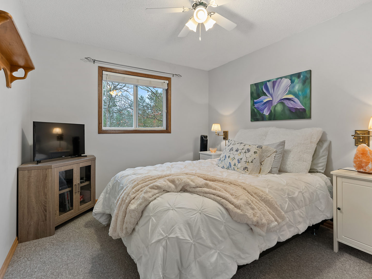 A bedroom with a bed, a small window, and a television.