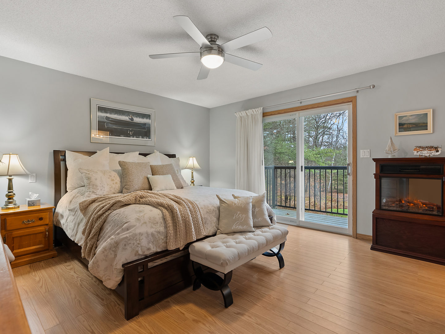 A large bedroom with a bed, hardwood floors, and glass doors leading out to a small balcony.