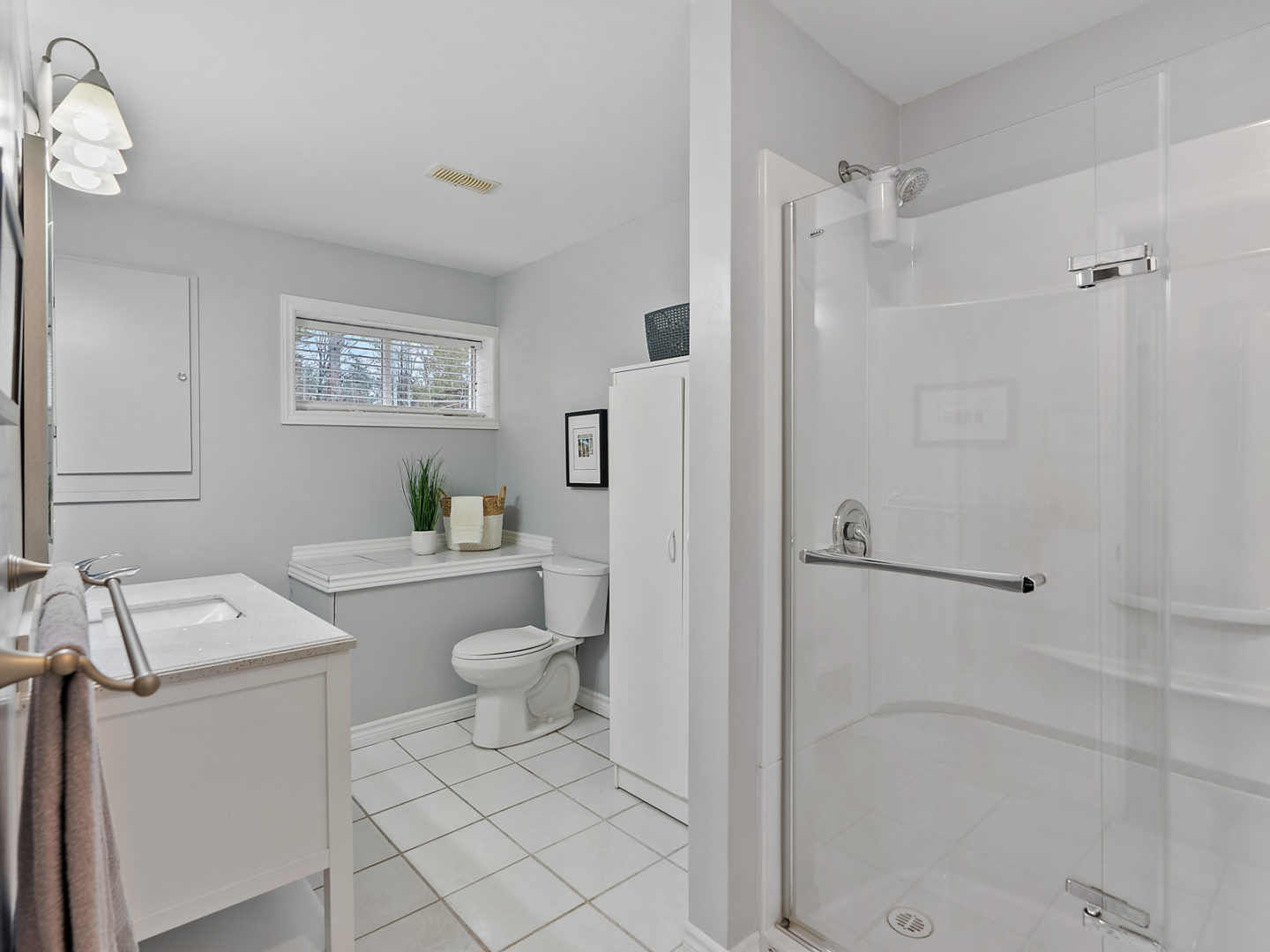 A big bathroom with tile flooring, a toilet, a sink, and a walk-in shower.