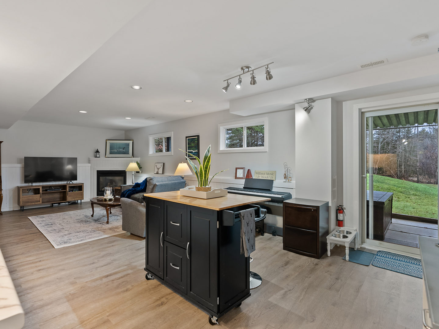 An open-concept living space with a small portable rolling island, seating, and a television.