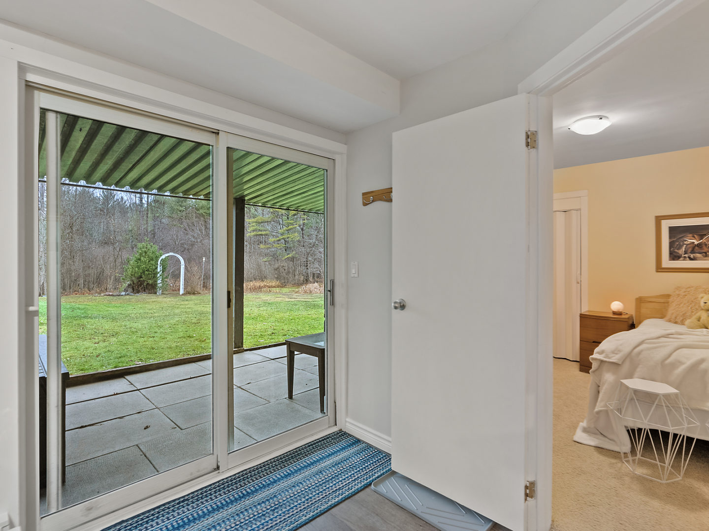 A glass door leading outdoors on the lower level of a raised bungalow. A bedroom can be seen through a door to the right.