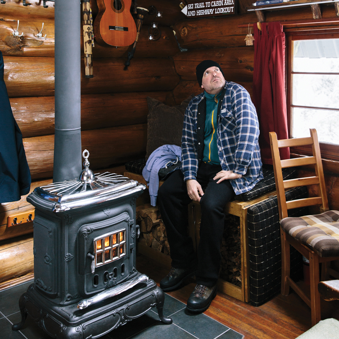Pete sitting beside the woodstove in his cabin