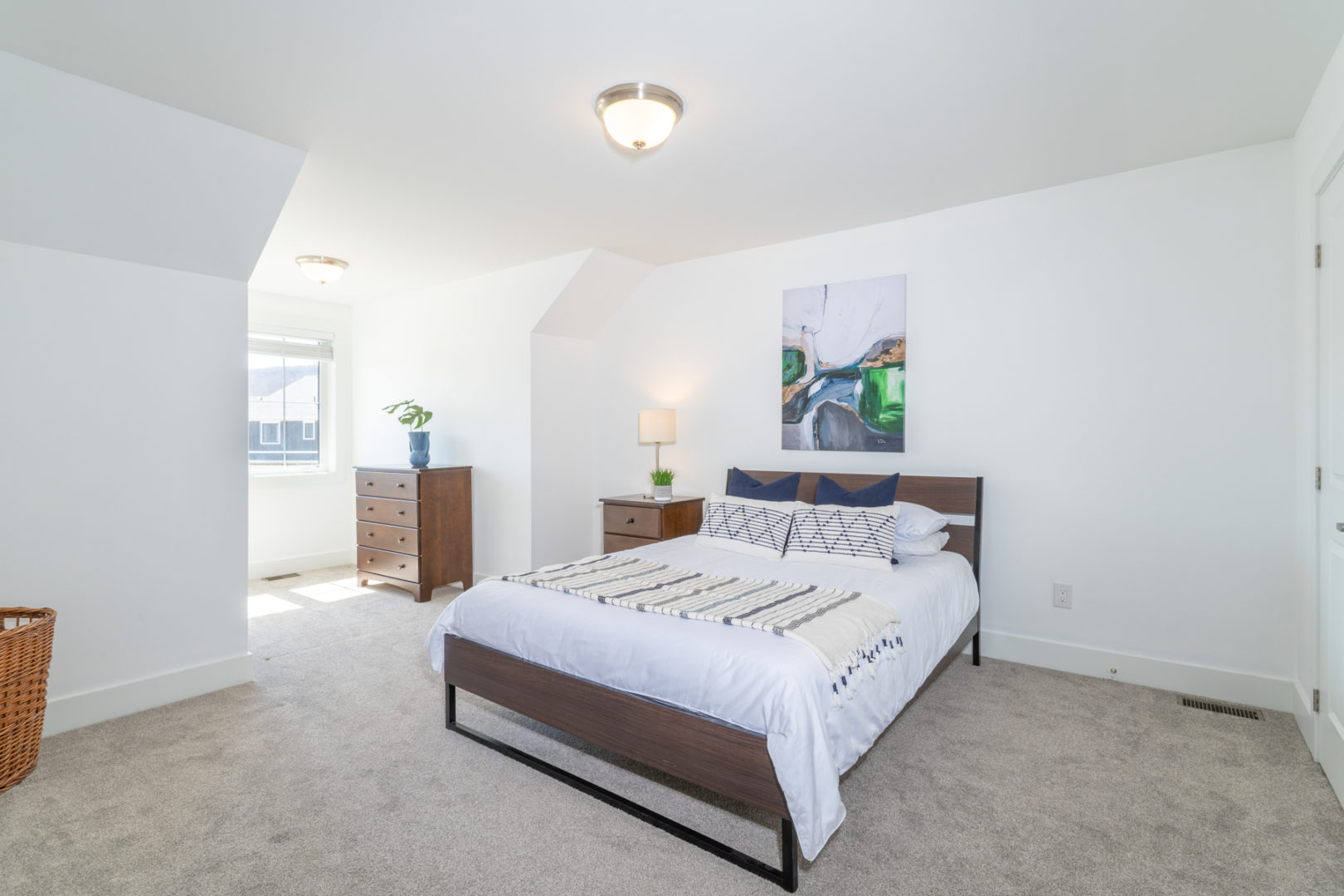 A large, bright bedroom with a spacious bed and carpeted flooring.