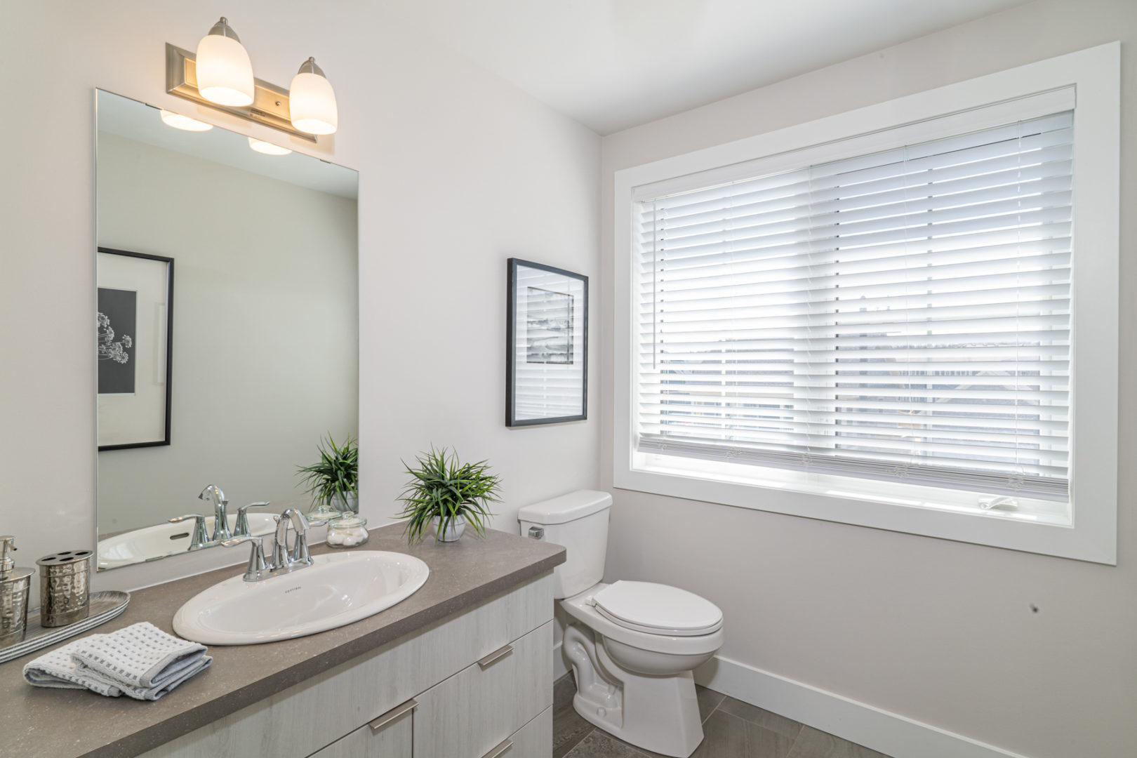 A small, bright bathroom with a toilet, a sink, and a large window.