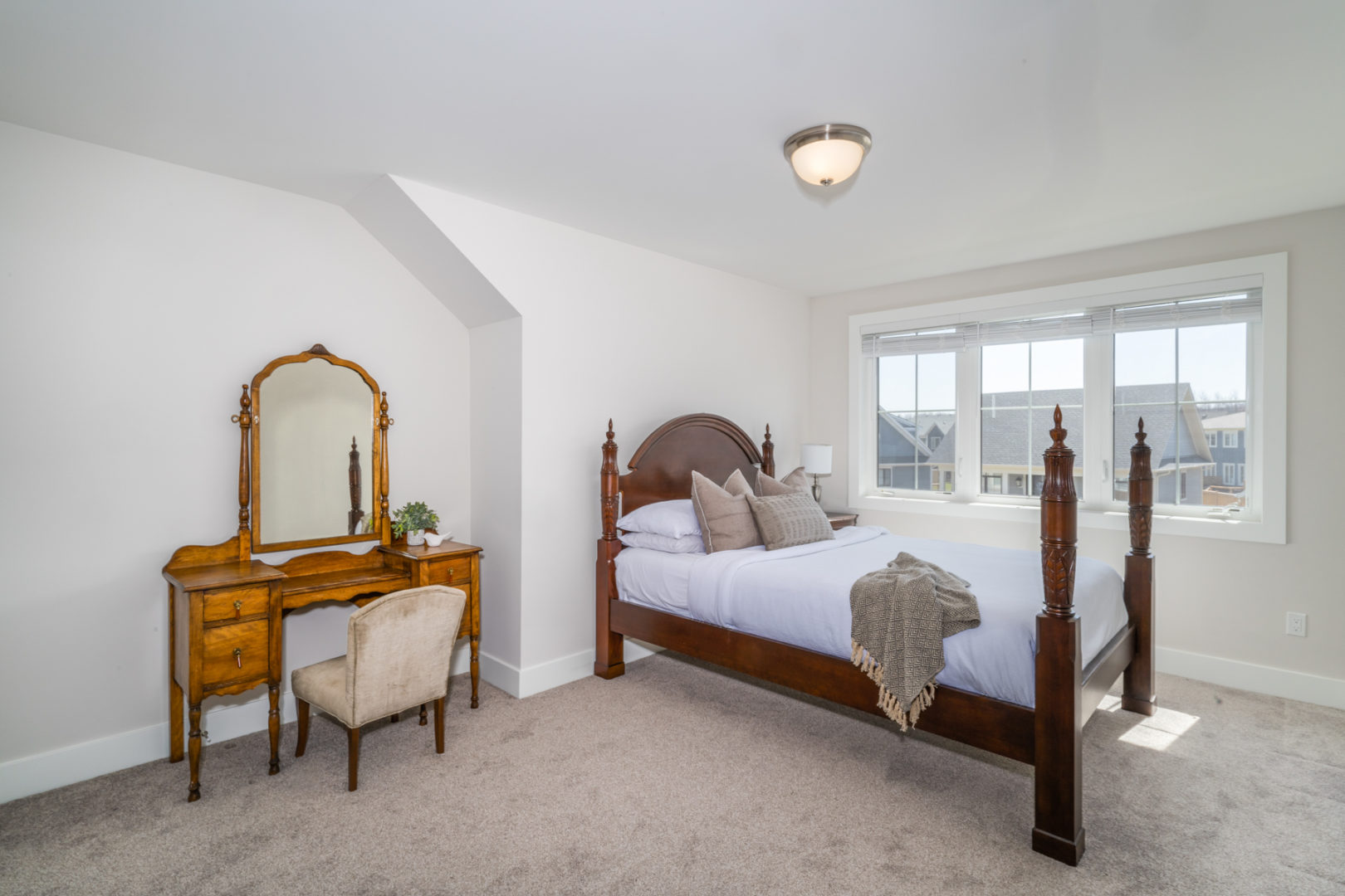 A large bedroom with a small bed and a vanity with a mirror and chair.