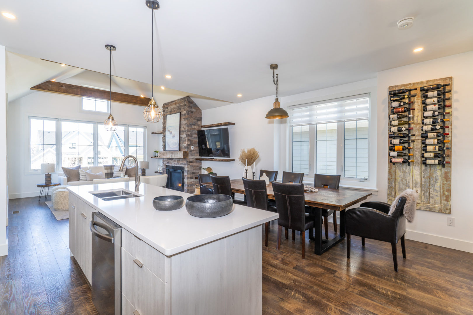 An open-concept space with a kitchen island, a dining room table and chairs, and a living area with couches and a television on the other side of the room.