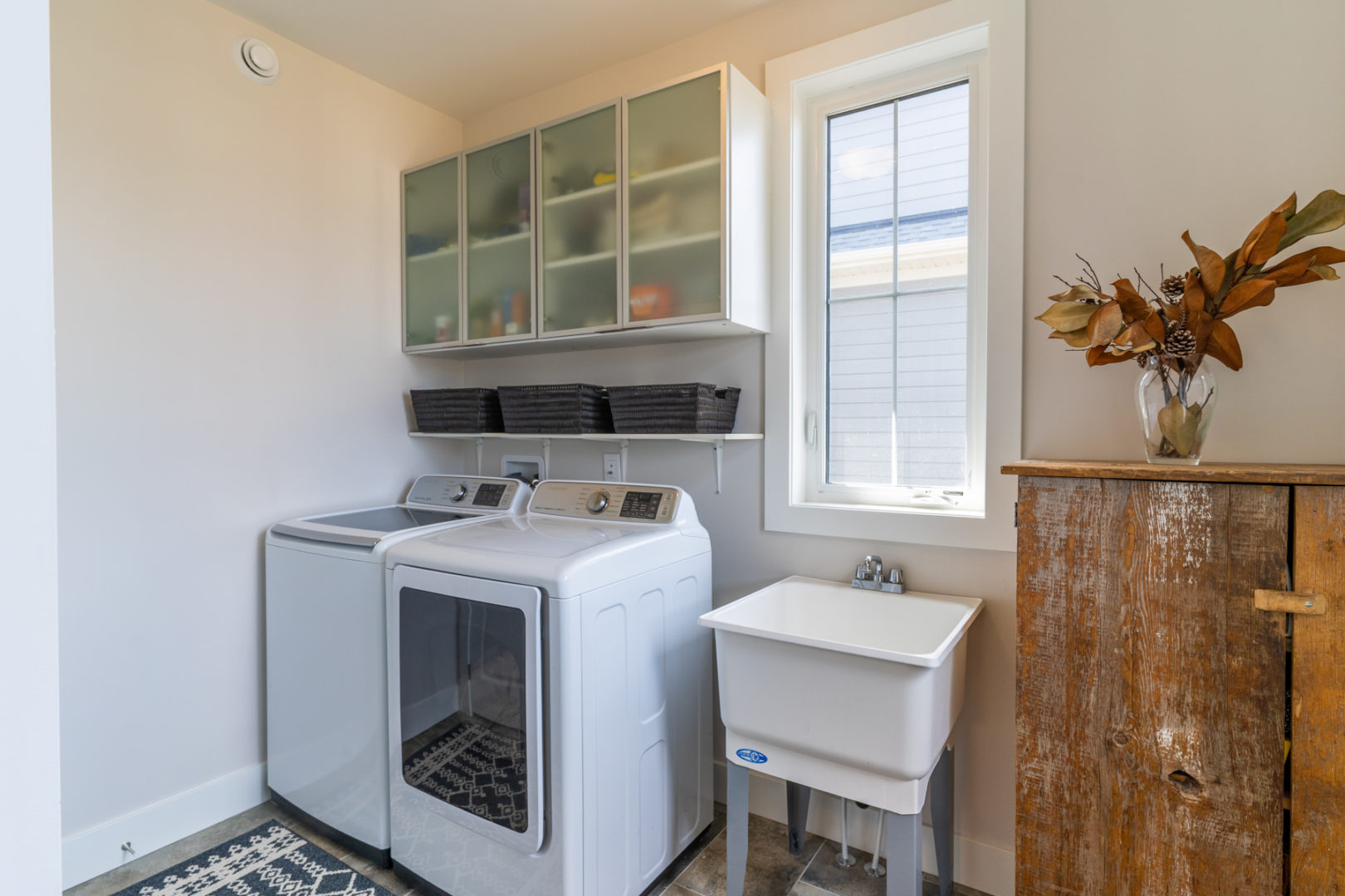 A modest laundry room space with a washing machine, a dryer, and a small sink.