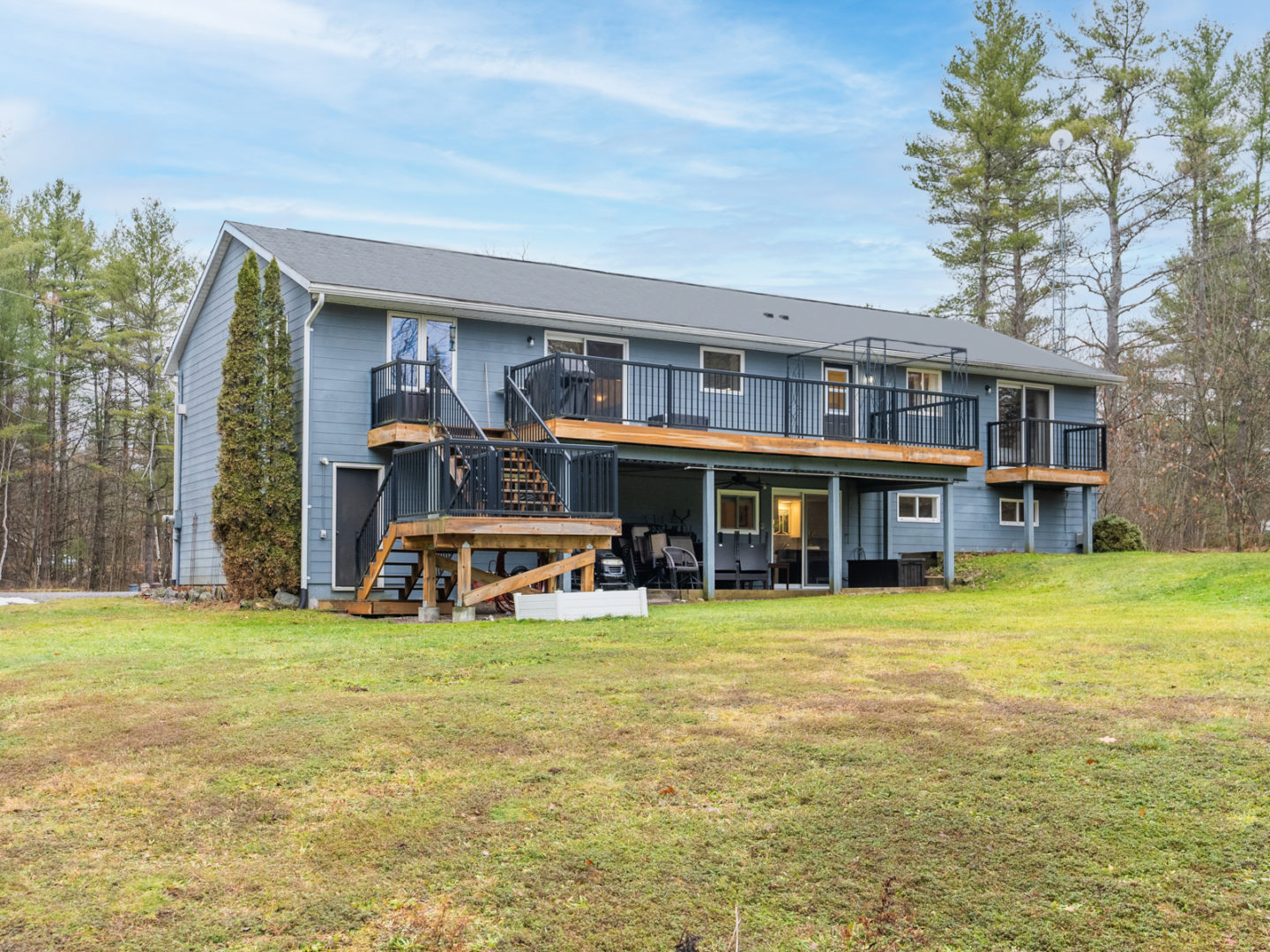 The back of a raised bungalow, with a large deck spanning the back side of the house.