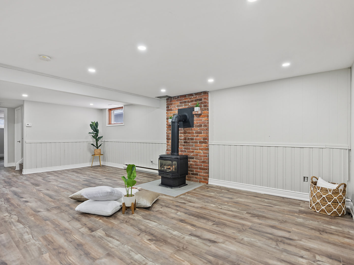 A bright, open, bare downstairs space with hardwood floors and a fireplace.