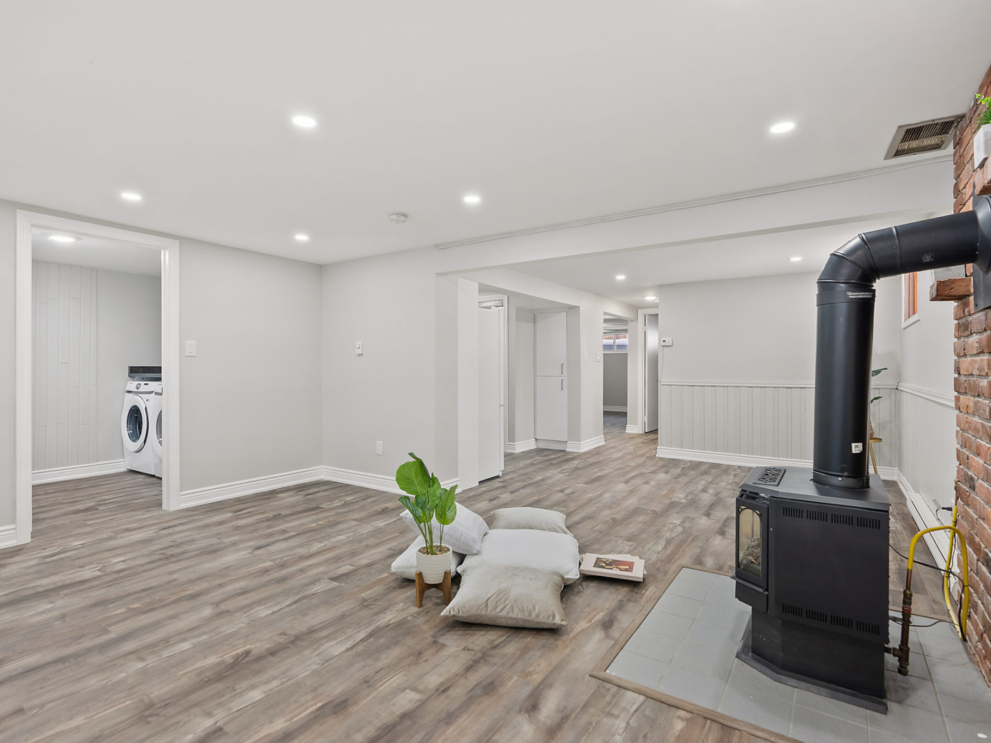 A bright, open, bare downstairs space with hardwood floors, a fireplace, and a small kitchen.