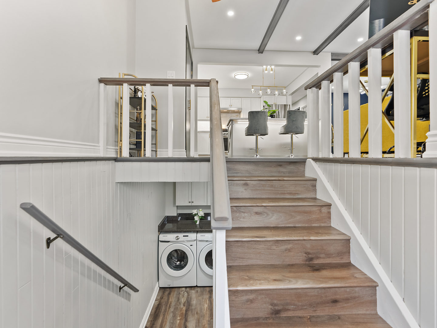 In the front entrance of a home, a staircase leads up into the main living area while another leads down into a downstairs laundry and living space.
